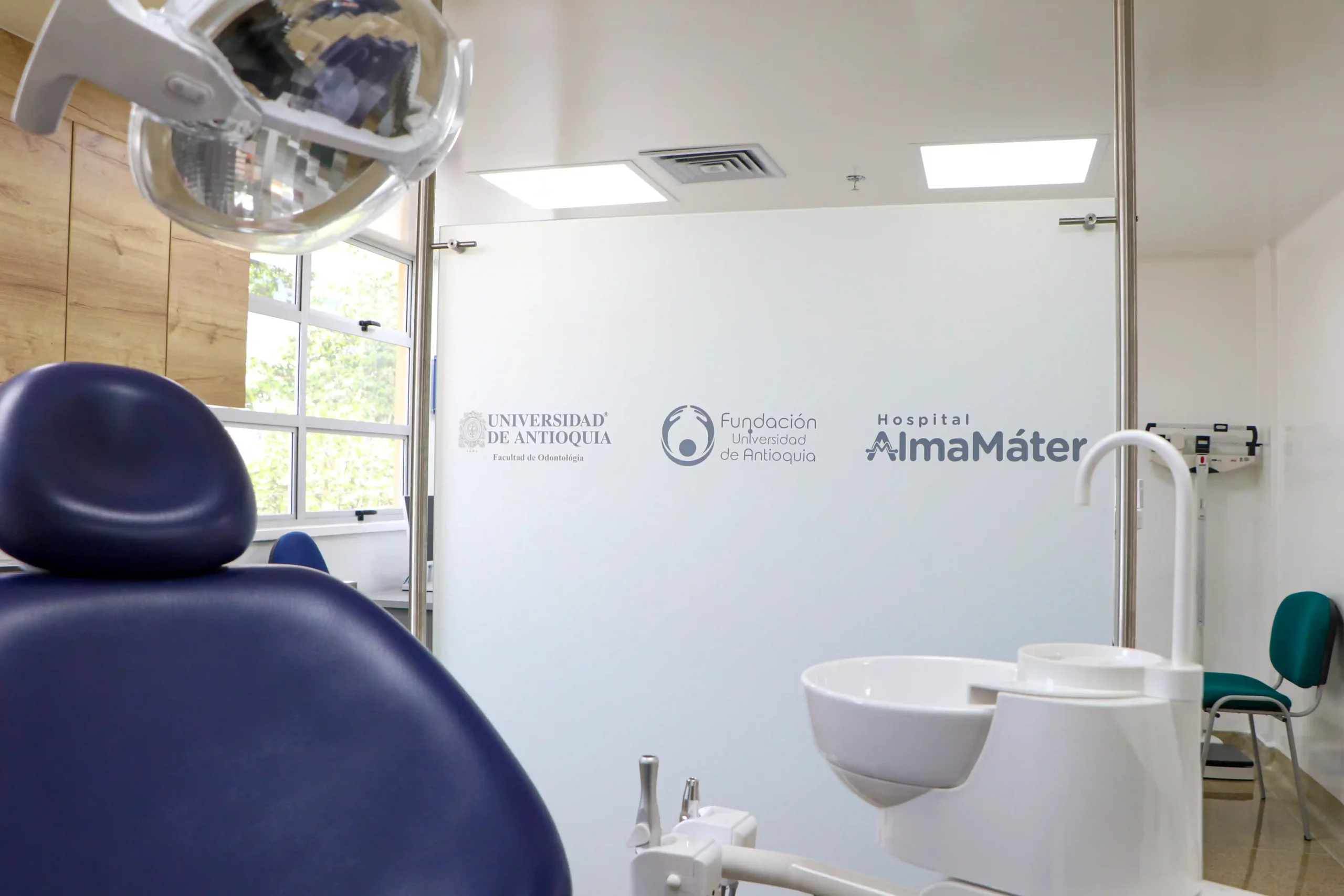 Instalaciones de odontología con silla, iluminación y diversos instrumentos. En un vidrio se observan los logos de los aliados.